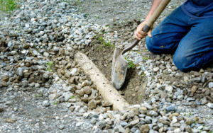 Man Digging Out French Drain In Driveway To Clean Out